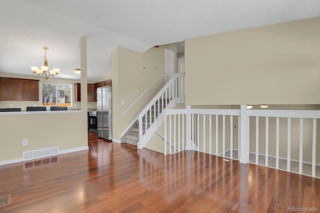 243 Madison Dr, Bennett, CO 80102 - interior space featuring wood finished floors, visible vents, baseboards, a chandelier, and a textured ceiling