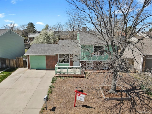 243 Madison Dr, Bennett, CO 80102 - split level home featuring a chimney, fence, a shingled roof, driveway, and brick siding