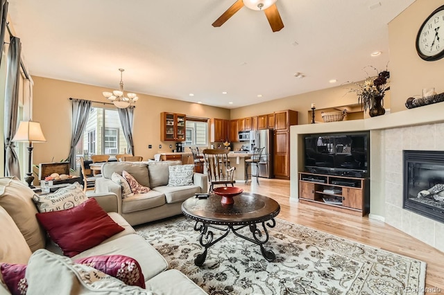 10463 Nucla St, Commerce City, CO 80022 - living area featuring light wood-style flooring, ceiling fan, a chandelier, and a tile fireplace