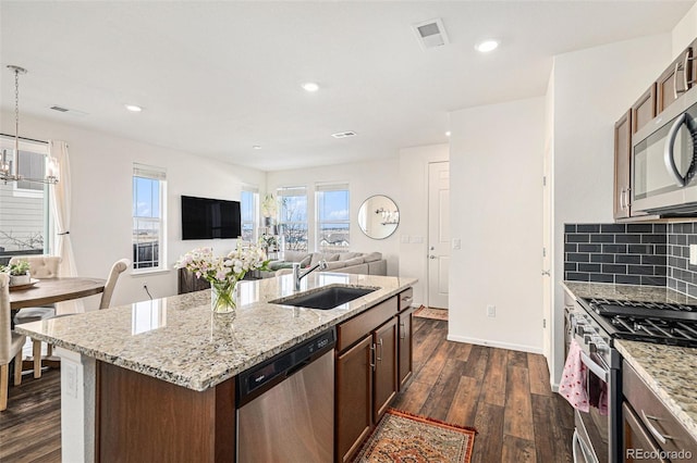 kitchen featuring sink, hanging light fixtures, stainless steel appliances, dark hardwood / wood-style floors, and an island with sink