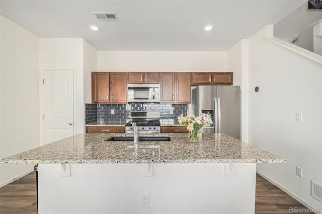 kitchen featuring stainless steel appliances, a breakfast bar, and a center island with sink