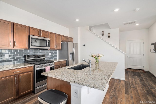 kitchen featuring sink, a breakfast bar, appliances with stainless steel finishes, backsplash, and a center island with sink