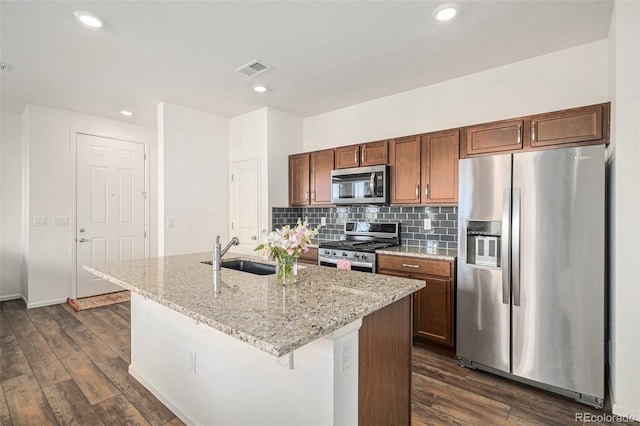 kitchen featuring appliances with stainless steel finishes, sink, backsplash, dark wood-type flooring, and a center island with sink