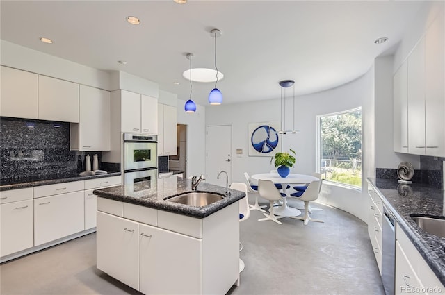 kitchen featuring pendant lighting, sink, white cabinetry, and a center island with sink