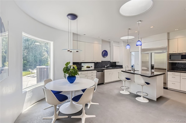 kitchen with a kitchen island, tasteful backsplash, white cabinets, hanging light fixtures, and built in appliances