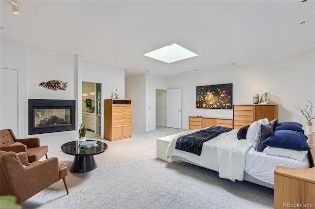 bedroom featuring light carpet, ensuite bath, and a skylight