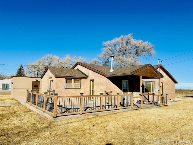 back of house with a wooden deck and a lawn