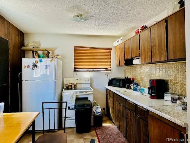 kitchen with tasteful backsplash, sink, a textured ceiling, and white appliances