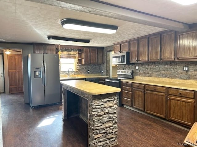 kitchen with appliances with stainless steel finishes, dark hardwood / wood-style floors, sink, backsplash, and dark brown cabinets