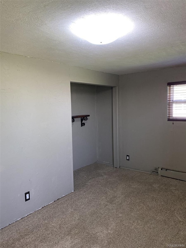 spare room featuring carpet, a baseboard heating unit, and a textured ceiling