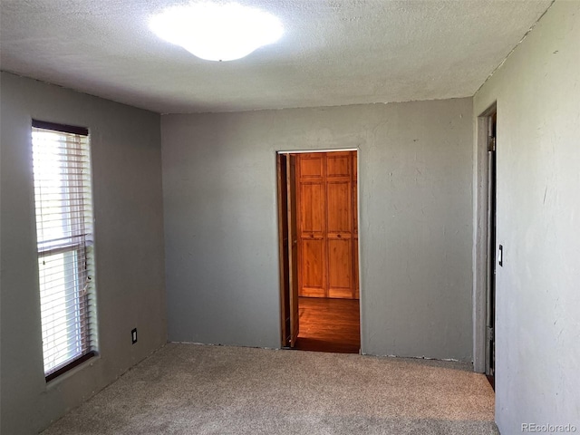 carpeted empty room with a textured ceiling