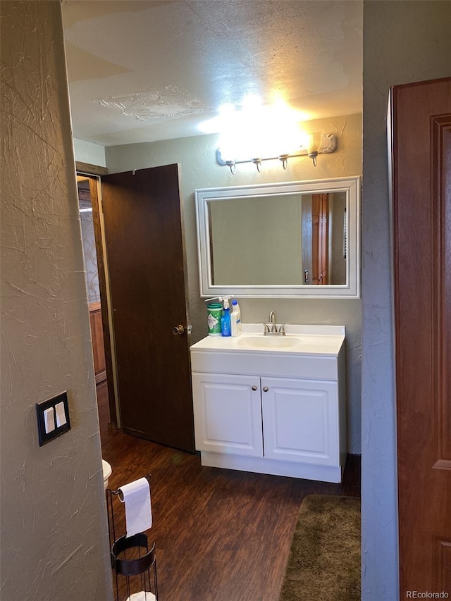 bathroom with hardwood / wood-style flooring, vanity, and a textured ceiling