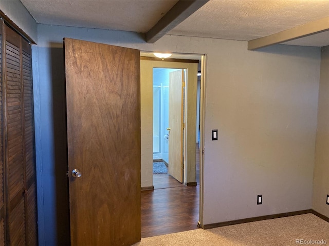 empty room with carpet, a textured ceiling, and beam ceiling