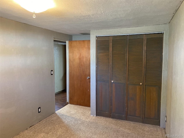 unfurnished bedroom with carpet, a closet, and a textured ceiling