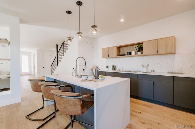 2530 Chase, Edgewater, CO 80215 - kitchen featuring light countertops, a breakfast bar, decorative backsplash, open shelves, and light wood-type flooring