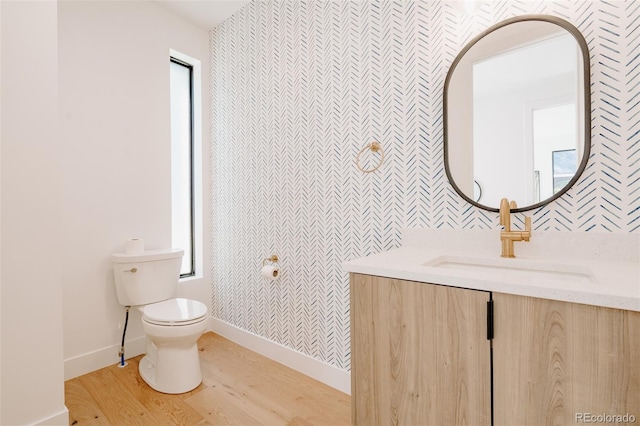 2530 Chase, Edgewater, CO 80215 - bathroom featuring toilet, wallpapered walls, wood finished floors, vanity, and baseboards