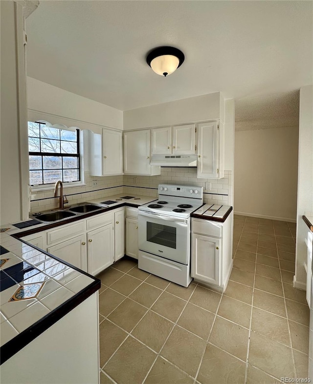 kitchen featuring tile counters, white cabinets, white electric range oven, and sink