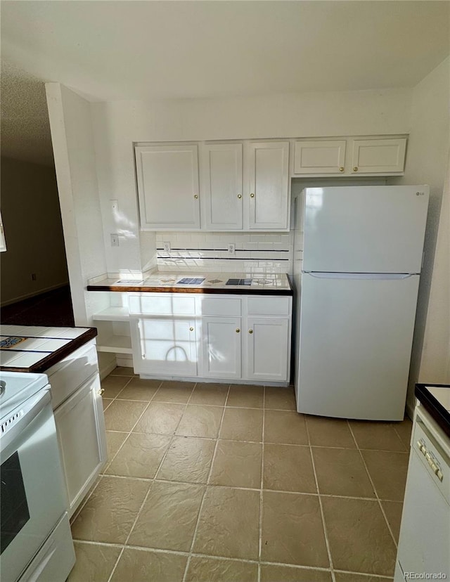 kitchen featuring white cabinets, light tile patterned flooring, white appliances, and backsplash