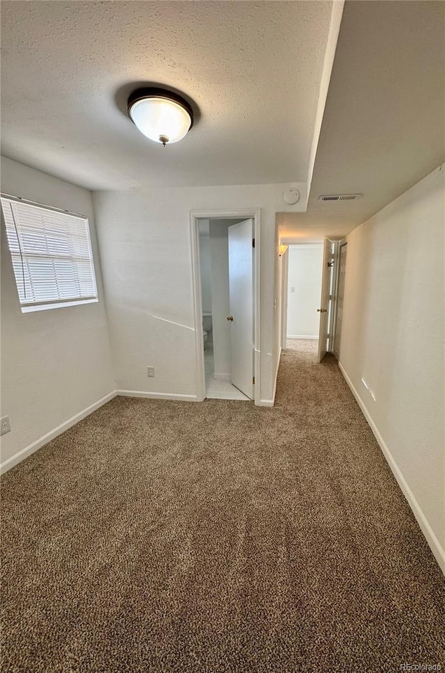 carpeted empty room with a textured ceiling