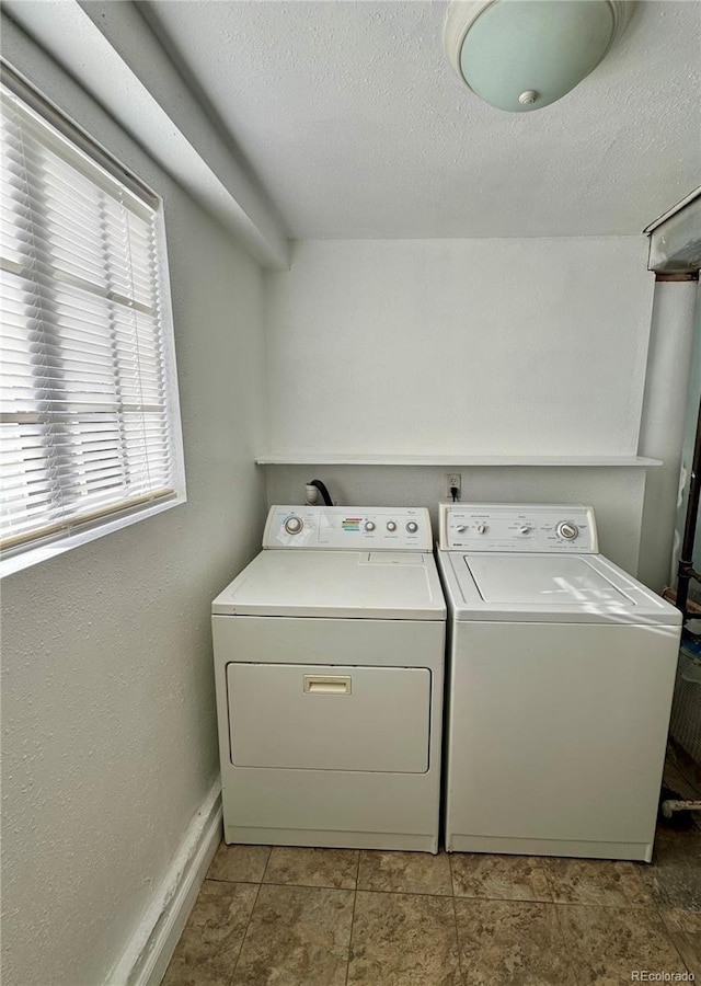 laundry room with washer and dryer, light tile patterned floors, and a textured ceiling