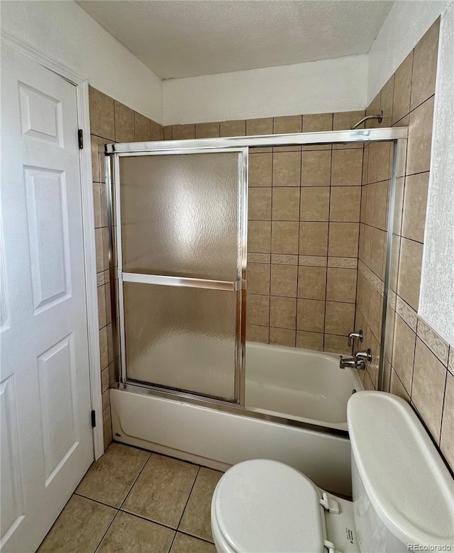 bathroom with shower / bath combination with glass door, a textured ceiling, tile patterned floors, and toilet