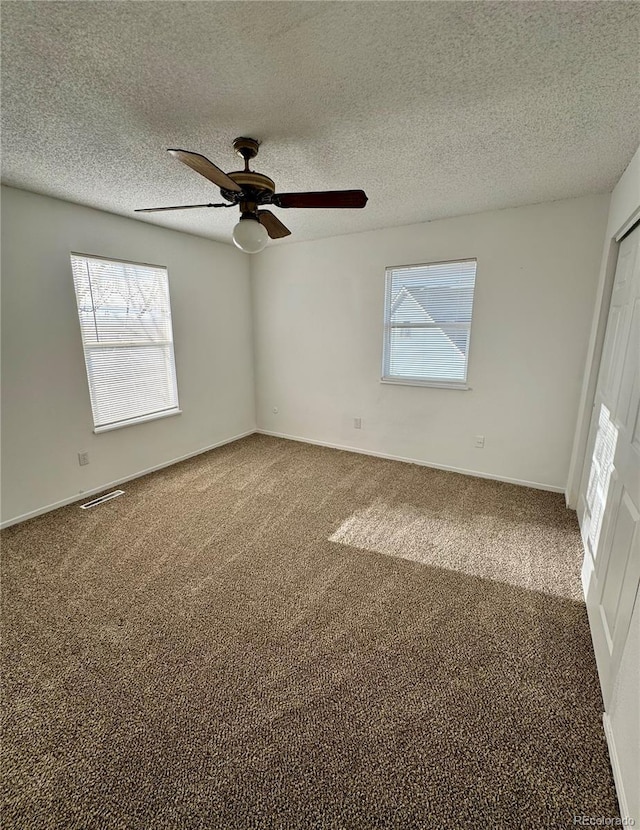 carpeted spare room with a textured ceiling and ceiling fan