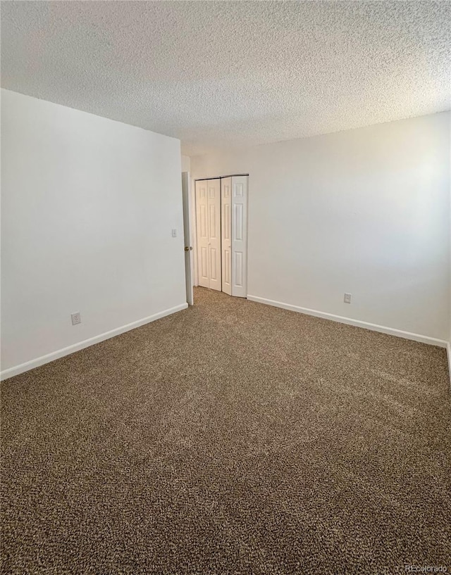 empty room with carpet floors and a textured ceiling