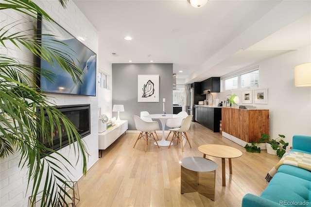 living area featuring recessed lighting, a tile fireplace, and light wood-style floors