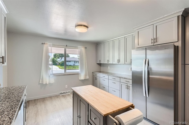 1785 S Zuni St, Denver, CO 80223 - kitchen with freestanding refrigerator, gray cabinetry, butcher block counters, light wood-type flooring, and a kitchen island