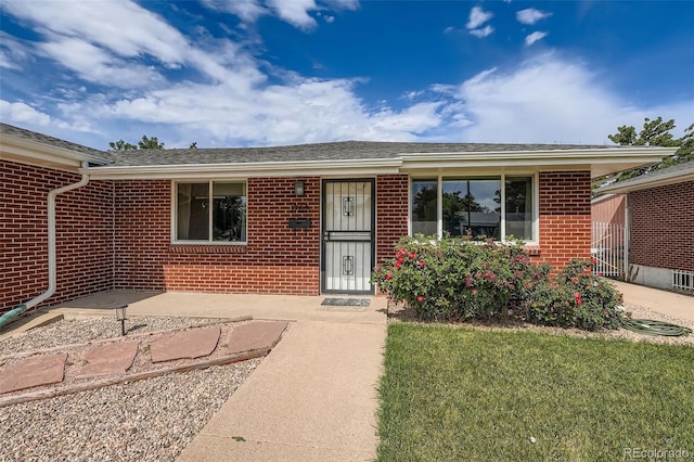 1785 S Zuni St, Denver, CO 80223 - doorway to property with brick siding and a yard
