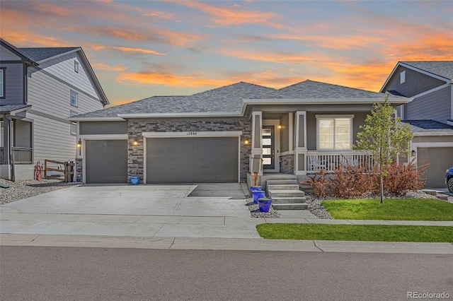prairie-style home featuring covered porch, driveway, roof with shingles, and a garage