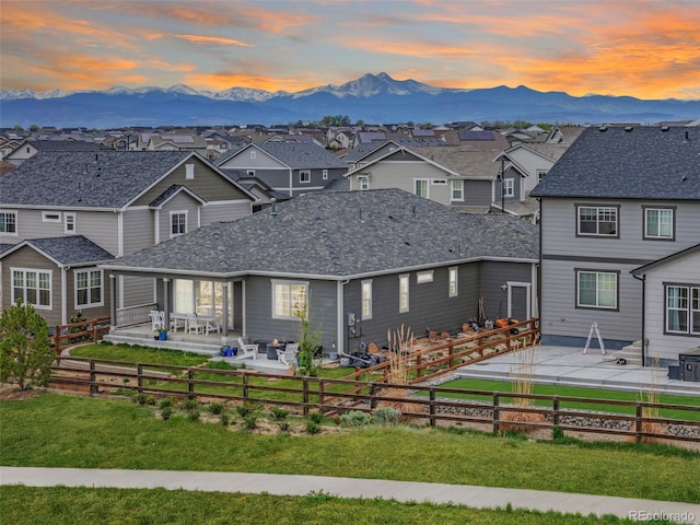 view of front of property featuring a fenced backyard, a residential view, a mountain view, and a patio area