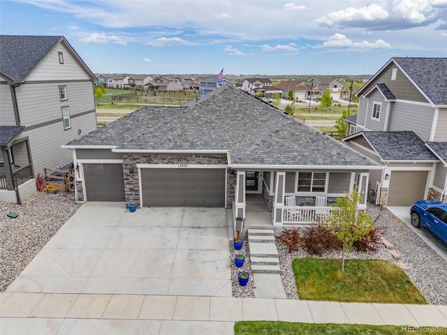 view of front facade featuring a residential view, a shingled roof, an attached garage, a porch, and driveway