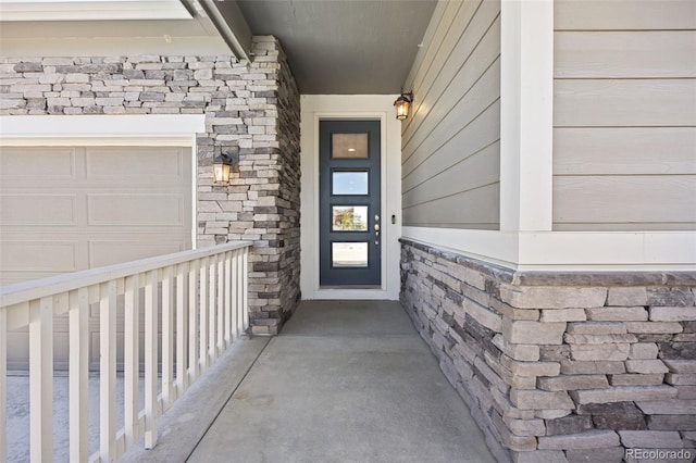doorway to property with a garage and stone siding