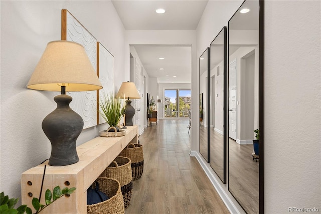 hallway featuring recessed lighting, baseboards, and wood finished floors