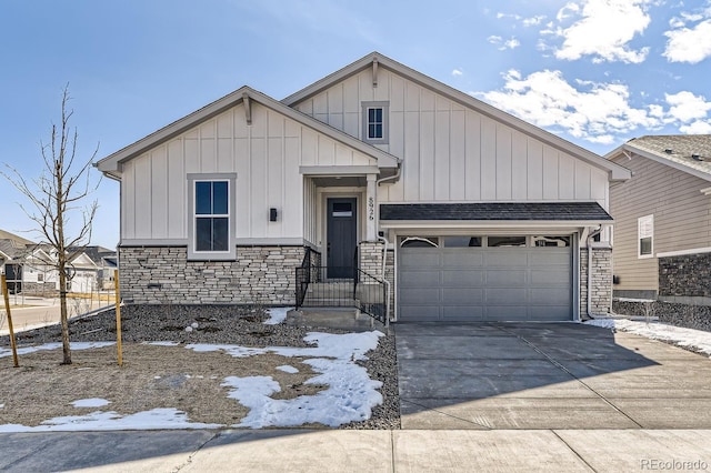 view of front facade with roof with shingles, concrete driveway, board and batten siding, a garage, and stone siding