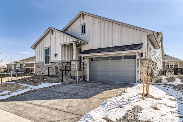 view of front facade featuring a shingled roof, central AC unit, board and batten siding, stone siding, and driveway