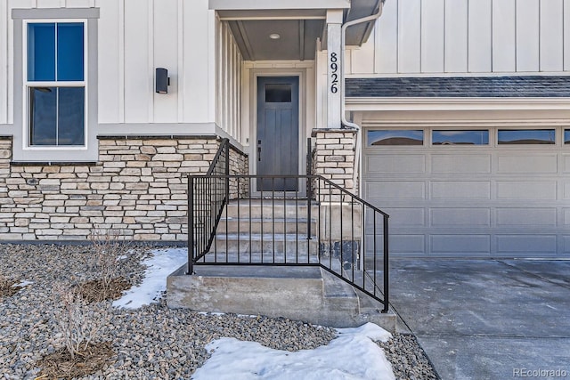 entrance to property with board and batten siding, concrete driveway, a garage, and roof with shingles