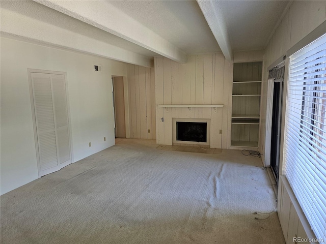 2525 S Dayton Way Unit 2307, Denver, CO 80231 - unfurnished living room featuring beamed ceiling, carpet floors, a fireplace, and a textured ceiling