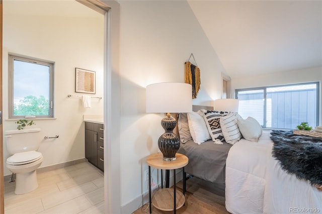 6892 Juniper Ct, Arvada, CO 80007 - bedroom with ensuite bathroom, lofted ceiling, and light wood-type flooring