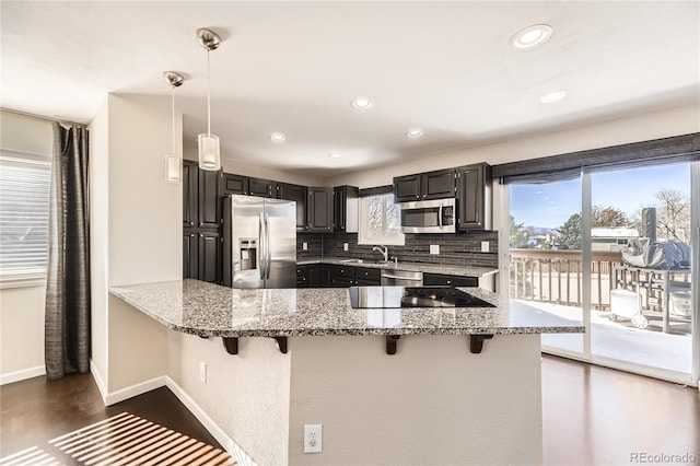 kitchen with pendant lighting, kitchen peninsula, decorative backsplash, and stainless steel appliances