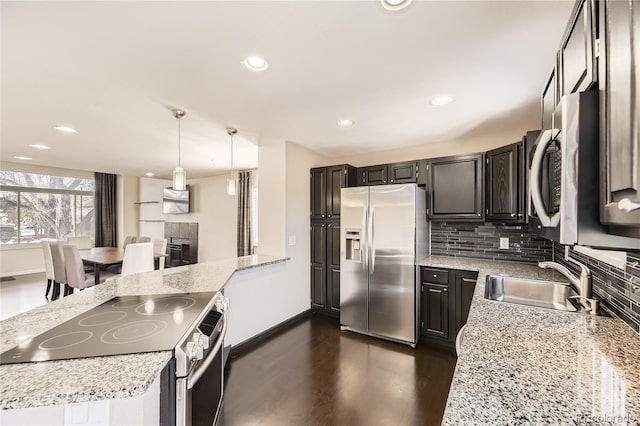 kitchen with stainless steel appliances, sink, backsplash, hanging light fixtures, and dark hardwood / wood-style flooring