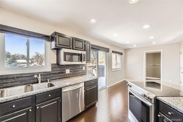 kitchen featuring light stone counters, stainless steel appliances, dark hardwood / wood-style floors, decorative backsplash, and sink