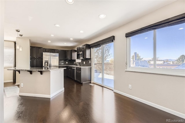 kitchen featuring stainless steel appliances, sink, a kitchen island, pendant lighting, and dark hardwood / wood-style flooring