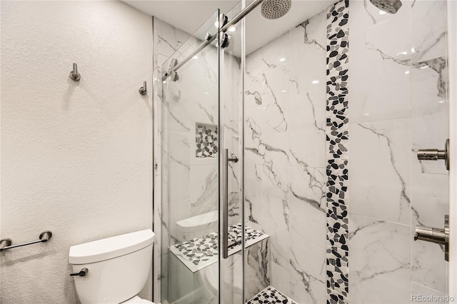 bathroom featuring toilet and a shower with shower door