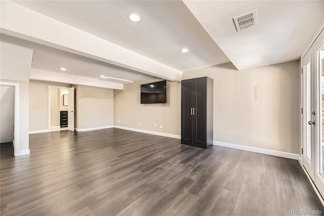 basement featuring a textured ceiling, a wealth of natural light, and dark hardwood / wood-style floors