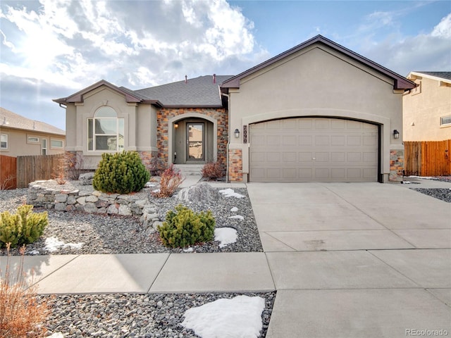7090 Silver Buckle Dr, Colorado Springs, CO 80923 - view of front of home with stucco siding, stone siding, fence, concrete driveway, and a garage