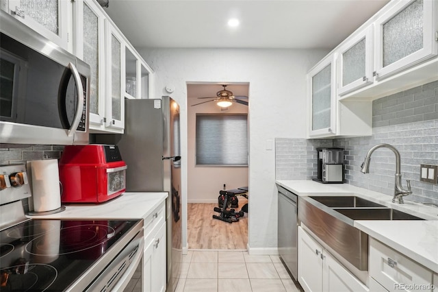 kitchen featuring decorative backsplash, ceiling fan, light tile patterned floors, appliances with stainless steel finishes, and white cabinetry