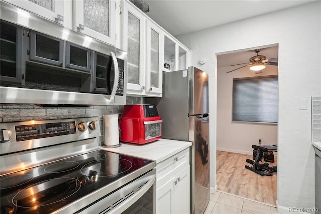 kitchen featuring white cabinets, ceiling fan, light tile patterned floors, and stainless steel appliances