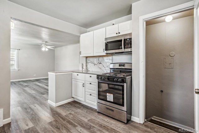 kitchen with white cabinetry, appliances with stainless steel finishes, hardwood / wood-style flooring, ceiling fan, and decorative backsplash